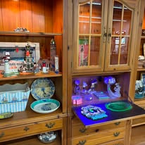 A wooden hutch with china plates, glassware and a lit display case